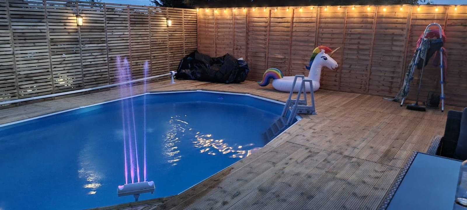 Landscaped UK garden with a lit outdoor pool at dusk — project example 3
